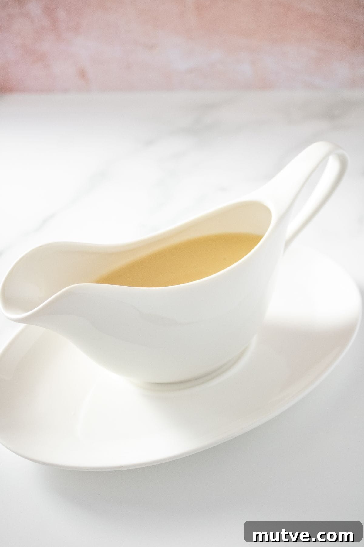 3-Ingredient Chicken Gravy Without Pan Drippings 5 White jug on white plate of Chicken Gravy.