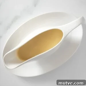 White jug on white plate of Chicken Gravy.