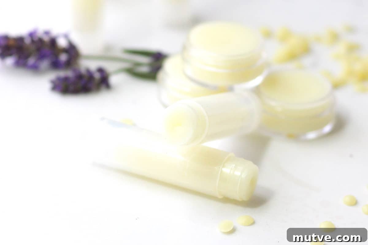 Beeswax Lip Balm Recipe: How to Make Soft, Hydrated Lips 6 a variety of beeswax lip balms laying on a white table surrounded by lavender flowers