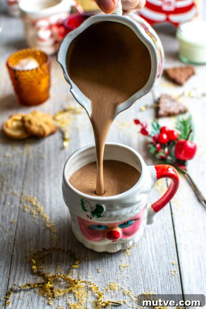 How to Make Mexican Mocha with Authentic Mexican Chocolate 2 mocha being poured into a Santa mug out of a pitcher.