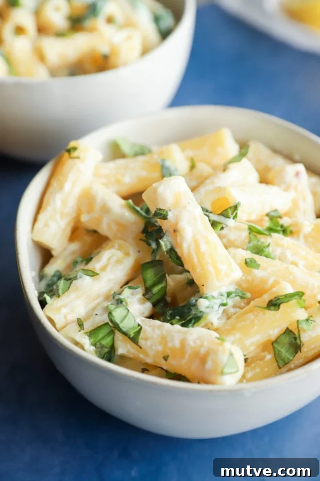 Side photo of pasta in bowl with cheese and arugula