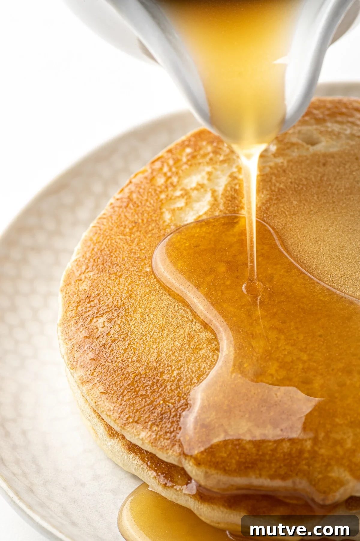 How to Make Keto Maple Syrup That Won't Crystallize 2 Pancakes being covered in syrup made from this keto maple syrup recipe.