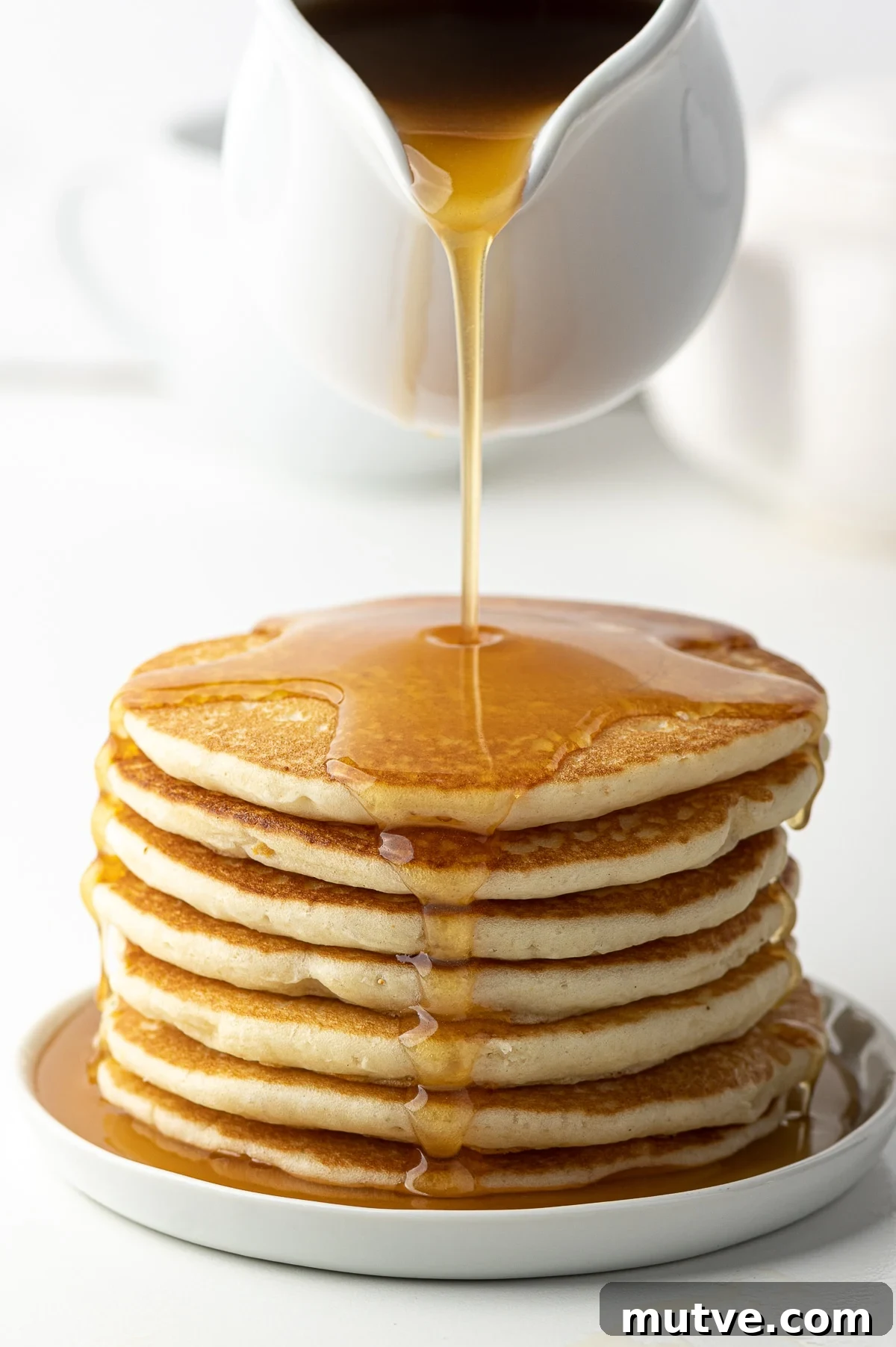 How to Make Keto Maple Syrup That Won't Crystallize 8 Keto maple syrup being poured over a stack of homemade pancakes.