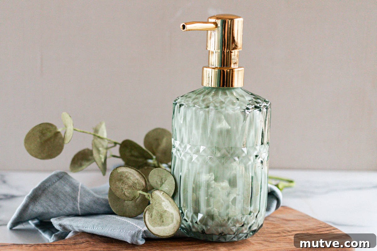 A green glass pump bottle of lotion on a wooden board with eucalyptus leaves. 