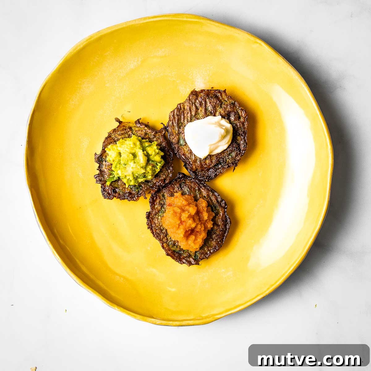 Crispy Oven Baked Brussels Sprouts Latkes 2 Three latkes with different toppings: applesauce, guacamole and sour cream.