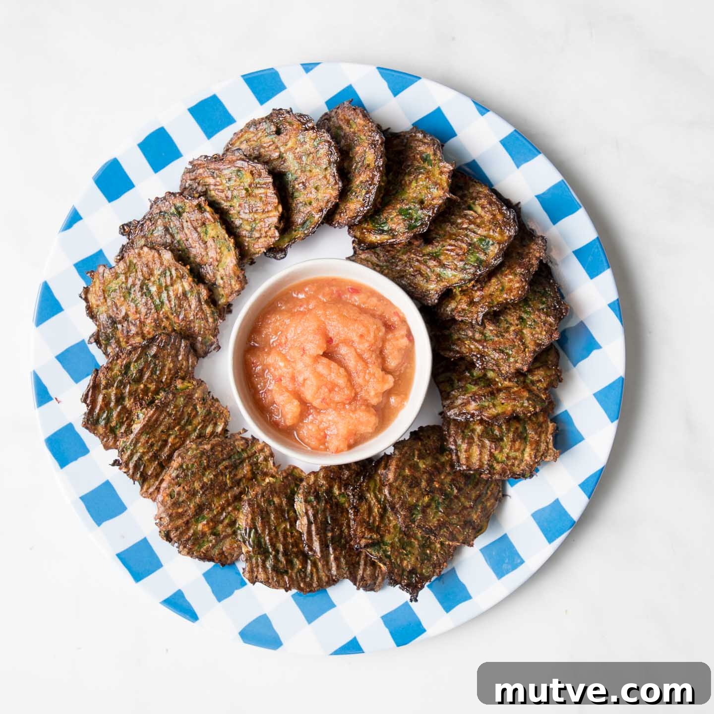 Crispy Oven Baked Brussels Sprouts Latkes 7 A plate of latkes with a dish of pink applesauce.