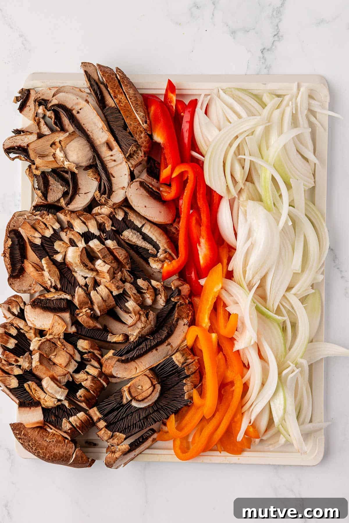 How to Make Portobello Mushroom Fajitas with Peppers and Onions 5 sliced portobello mushrooms, bell peppers, and onions on a sheet pan