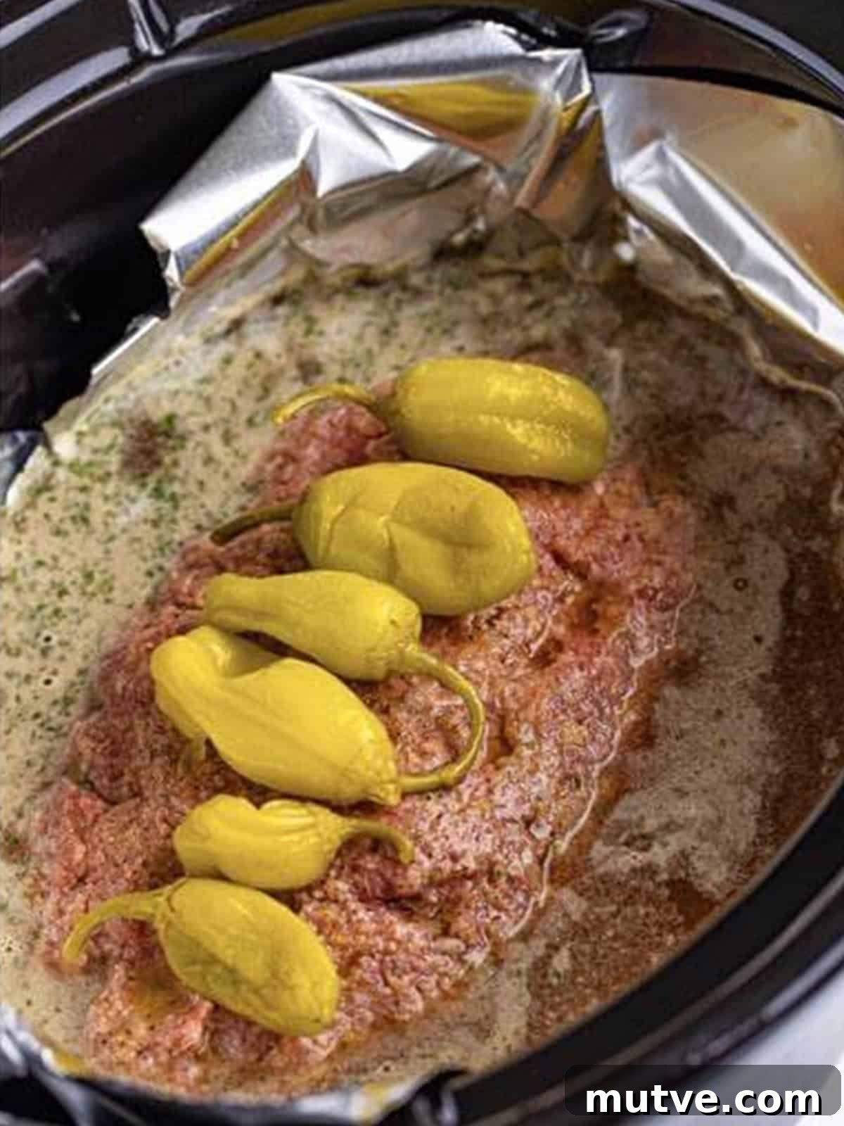 Slow Cooker Mississippi Meatloaf Recipe 12 Pepperoncini peppers placed on top of the crockpot meatloaf before cooking.