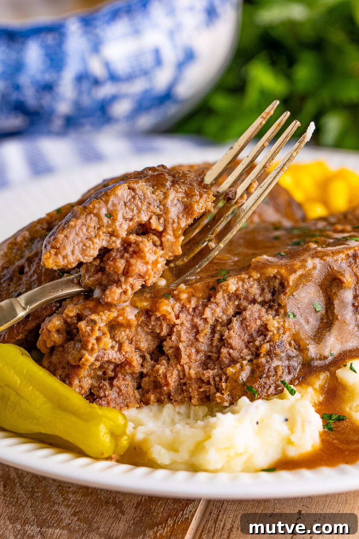 Slow Cooker Mississippi Meatloaf Recipe 16 Fork cutting into a slice of crockpot meatloaf with gravy over mashed potatoes.