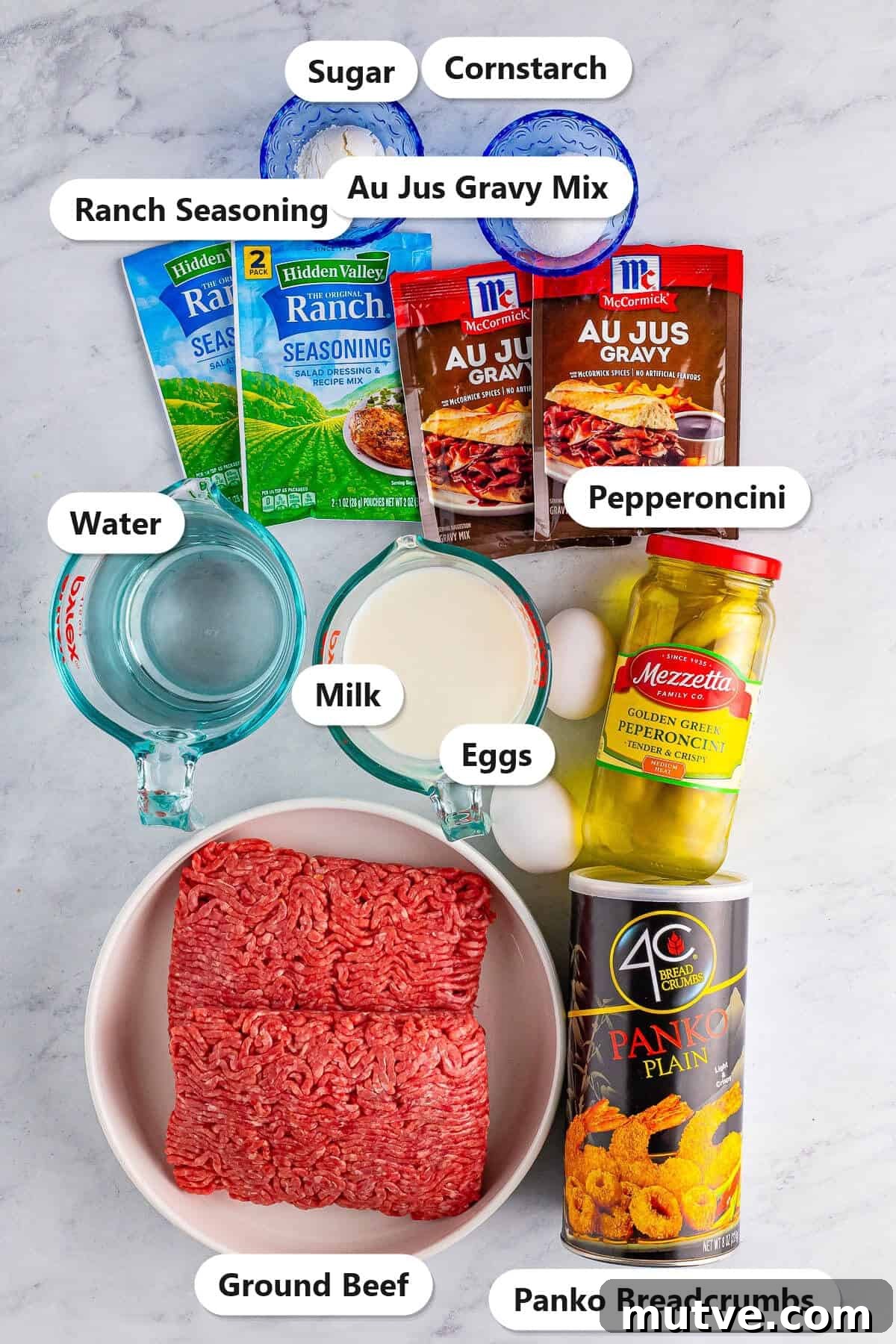 Slow Cooker Mississippi Meatloaf Recipe 3 Labeled ingredients for Mississippi crockpot meatloaf including ground beef, ranch seasoning, au jus gravy mix, pepperoncini, panko breadcrumbs, milk, eggs, sugar, cornstarch, and water.