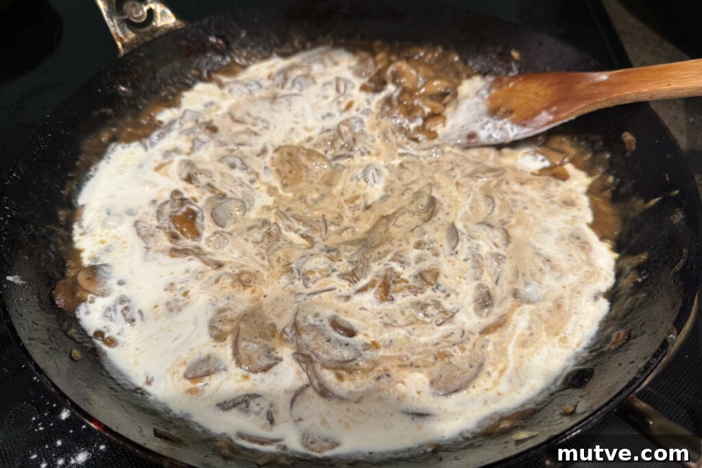 Adding cream to the mushroom and onion sauce.