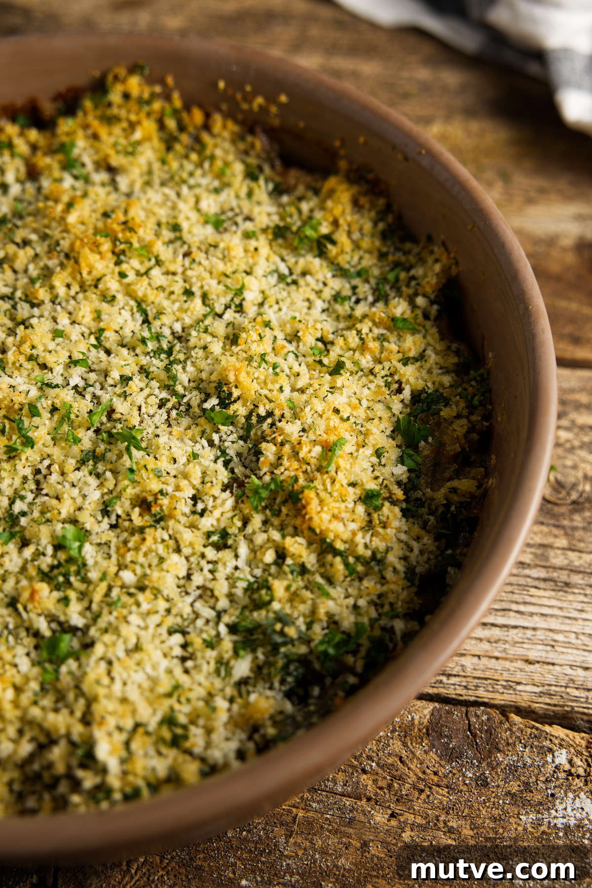 Casserole dish filled with green bean casserole resting on a rustic wood plank counter.