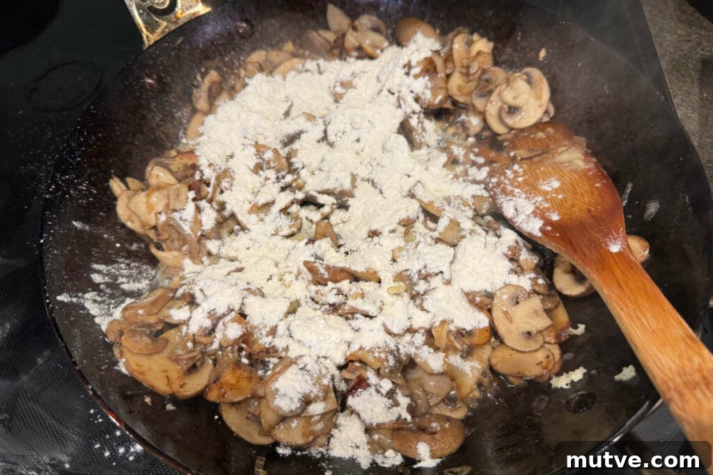 Adding flour to cooked mushrooms in the frying pan.