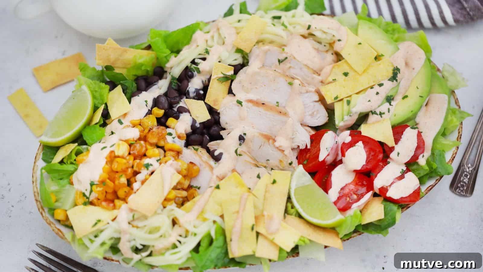 40 End-of-Summer Cookout Recipes to Celebrate Summer's Finale 15 A colorful chicken salad with avocado, black beans, corn, cherry tomatoes, and lime slices, presented in a white bowl.
