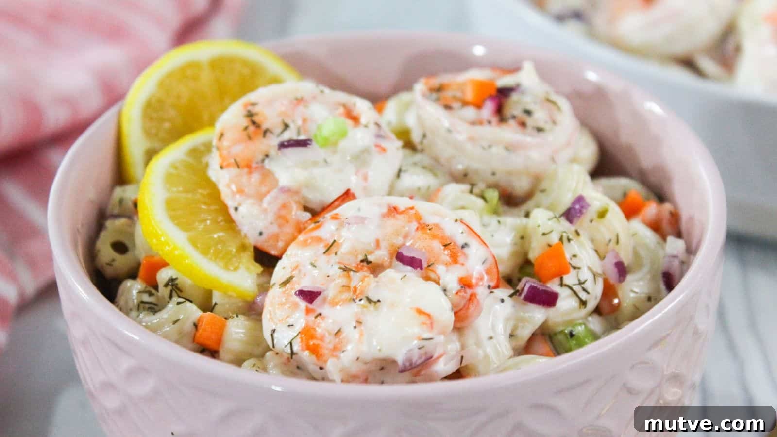40 End-of-Summer Cookout Recipes to Celebrate Summer's Finale 17 A bowl of shrimp pasta salad garnished with lemon slices and diced vegetables.