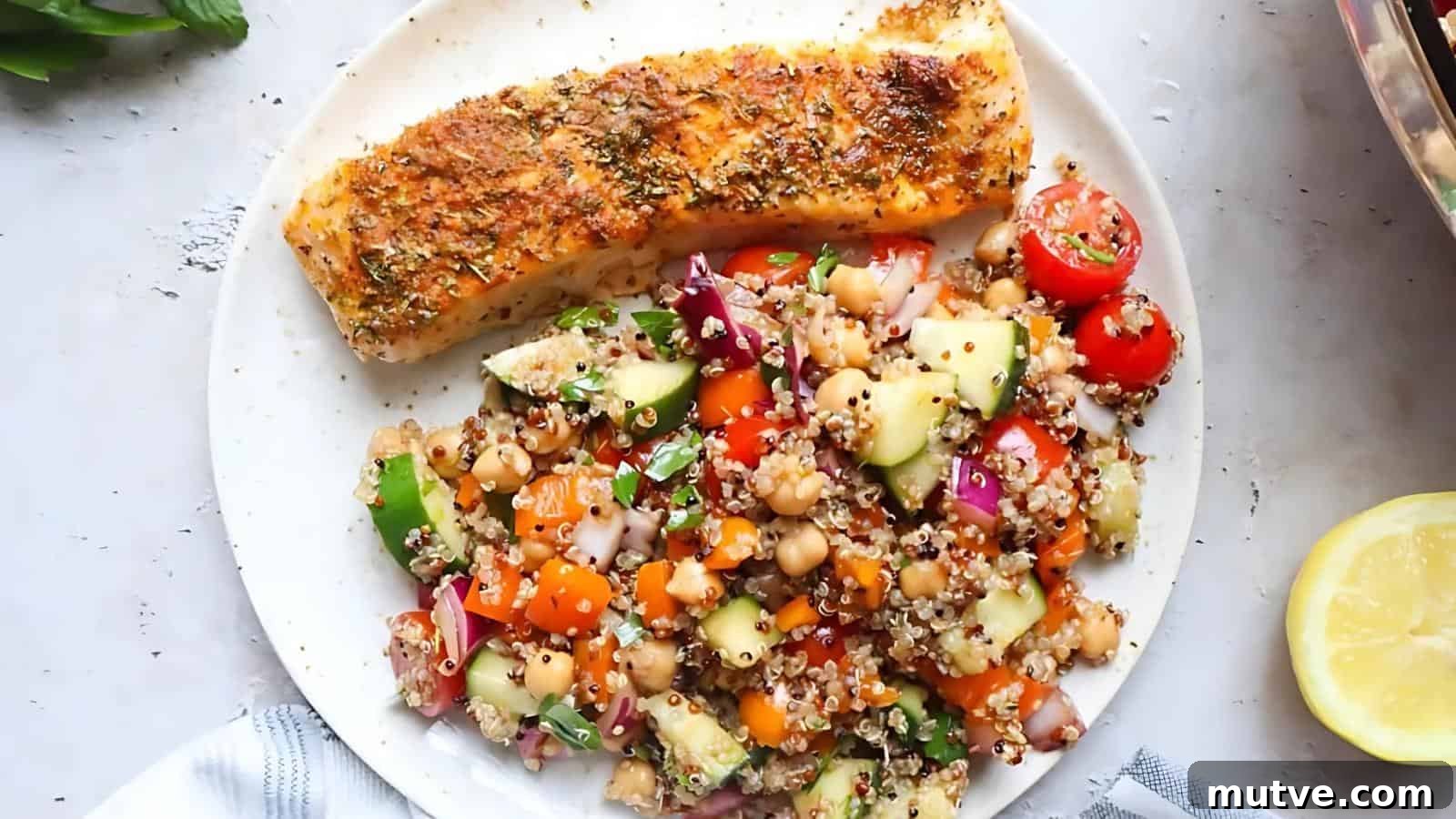 40 End-of-Summer Cookout Recipes to Celebrate Summer's Finale 23 A plate with a seasoned, baked salmon fillet and a colorful quinoa salad with chickpeas, cherry tomatoes, cucumber, red onion, parsley, and orange bell pepper.