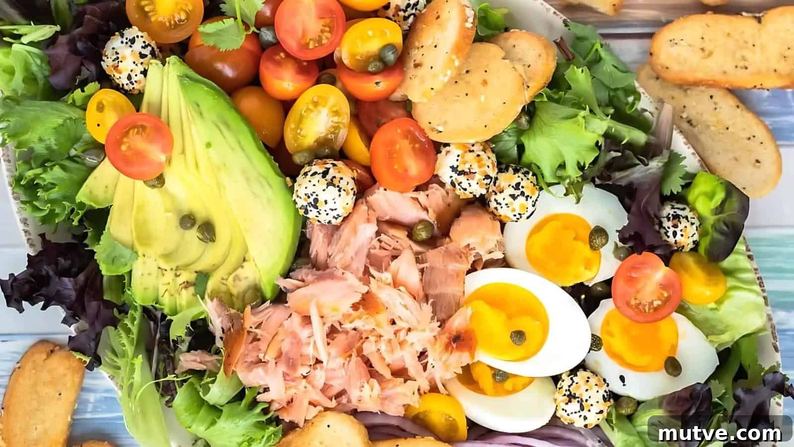 40 End-of-Summer Cookout Recipes to Celebrate Summer's Finale 39 A salad platter with mixed greens, sliced avocado, cherry tomatoes, soft-boiled eggs, smoked salmon, mini cheese balls with seeds, capers, and sliced bread.
