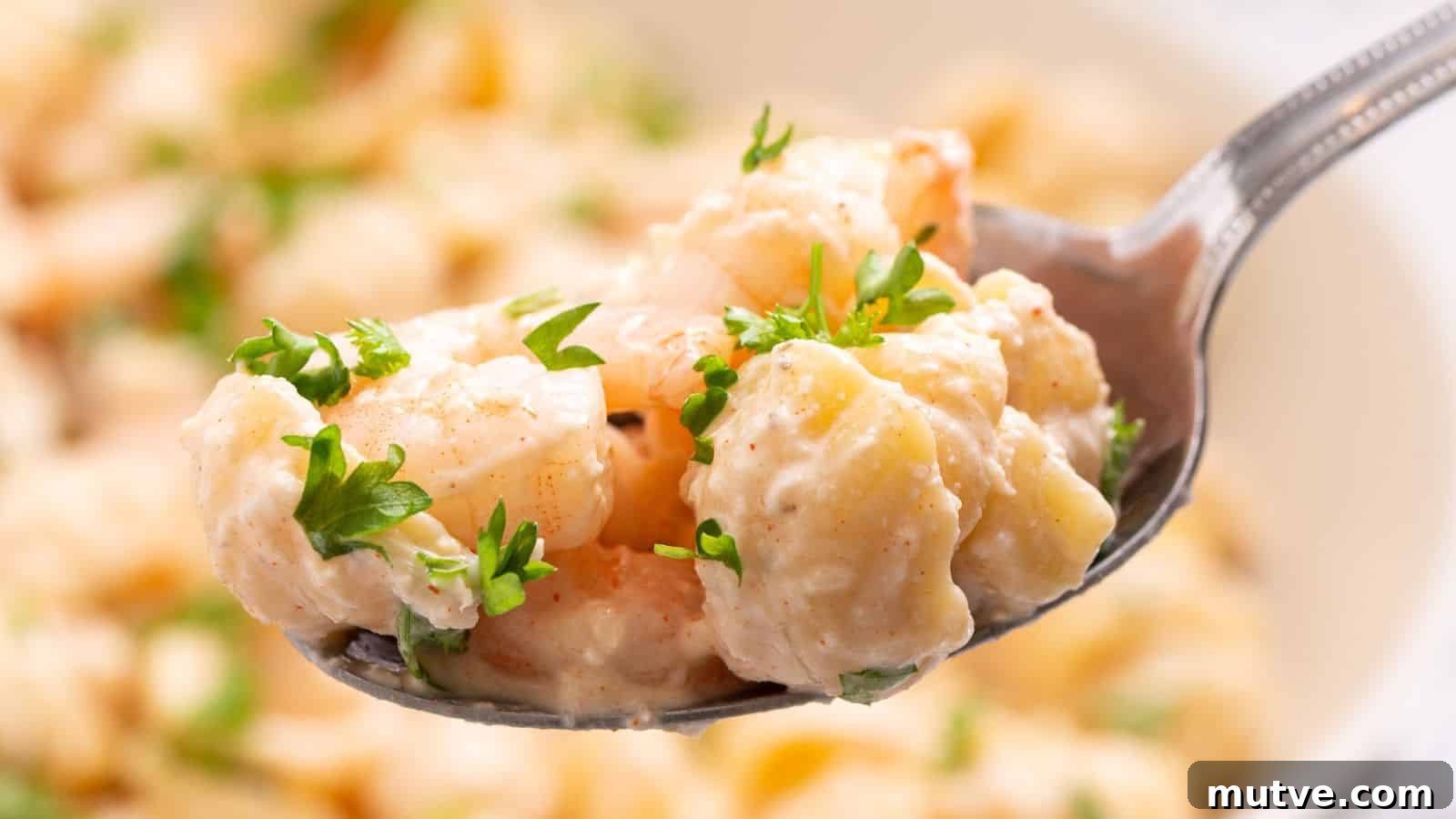 40 End-of-Summer Cookout Recipes to Celebrate Summer's Finale 6 Close-up of a spoon holding seafood pasta salad garnished with parsley, with more salad in the background.