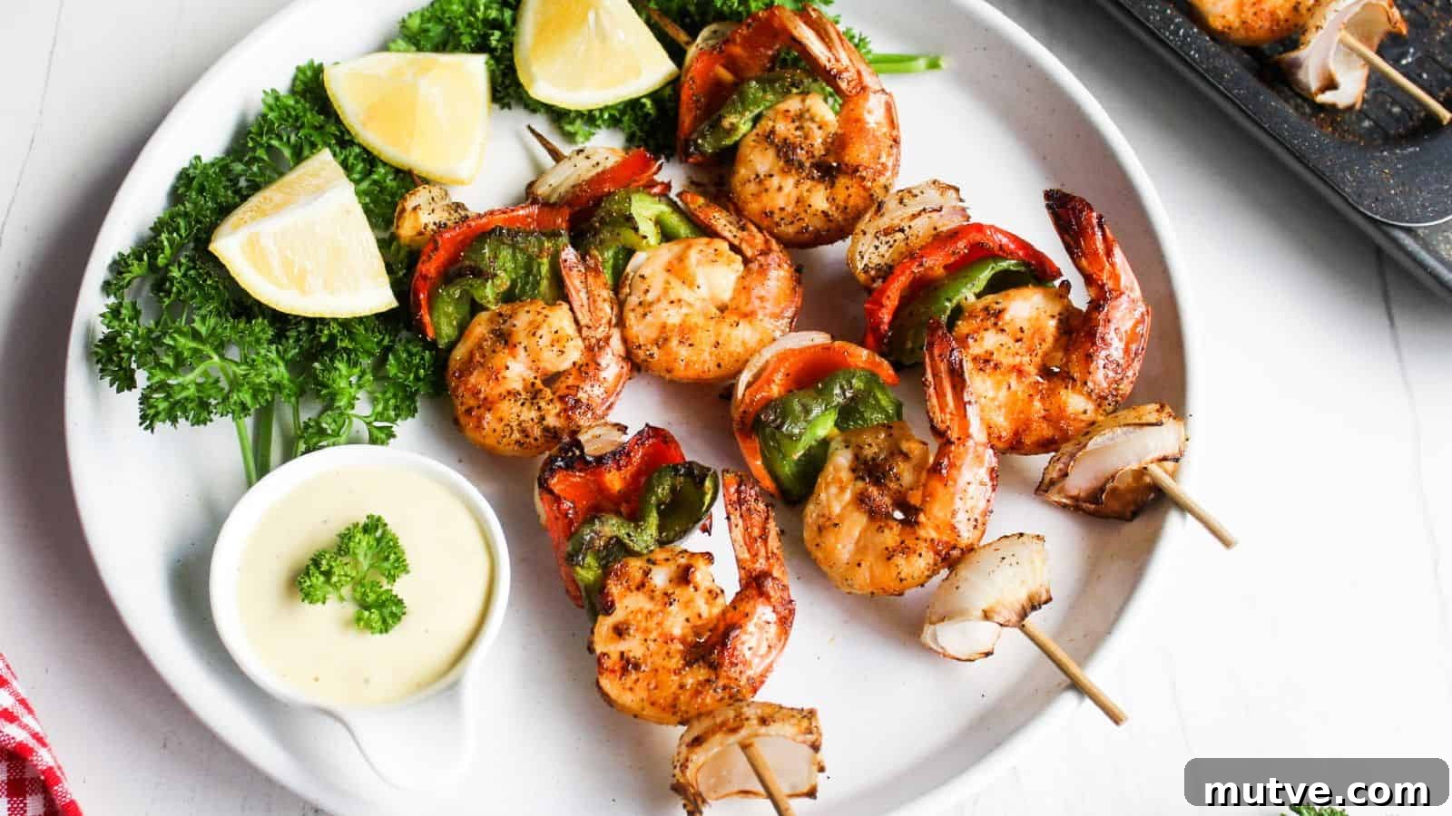 40 End-of-Summer Cookout Recipes to Celebrate Summer's Finale 7 Grilled shrimp skewers with red and green bell peppers, served with lemon wedges and a dipping sauce on a white plate.
