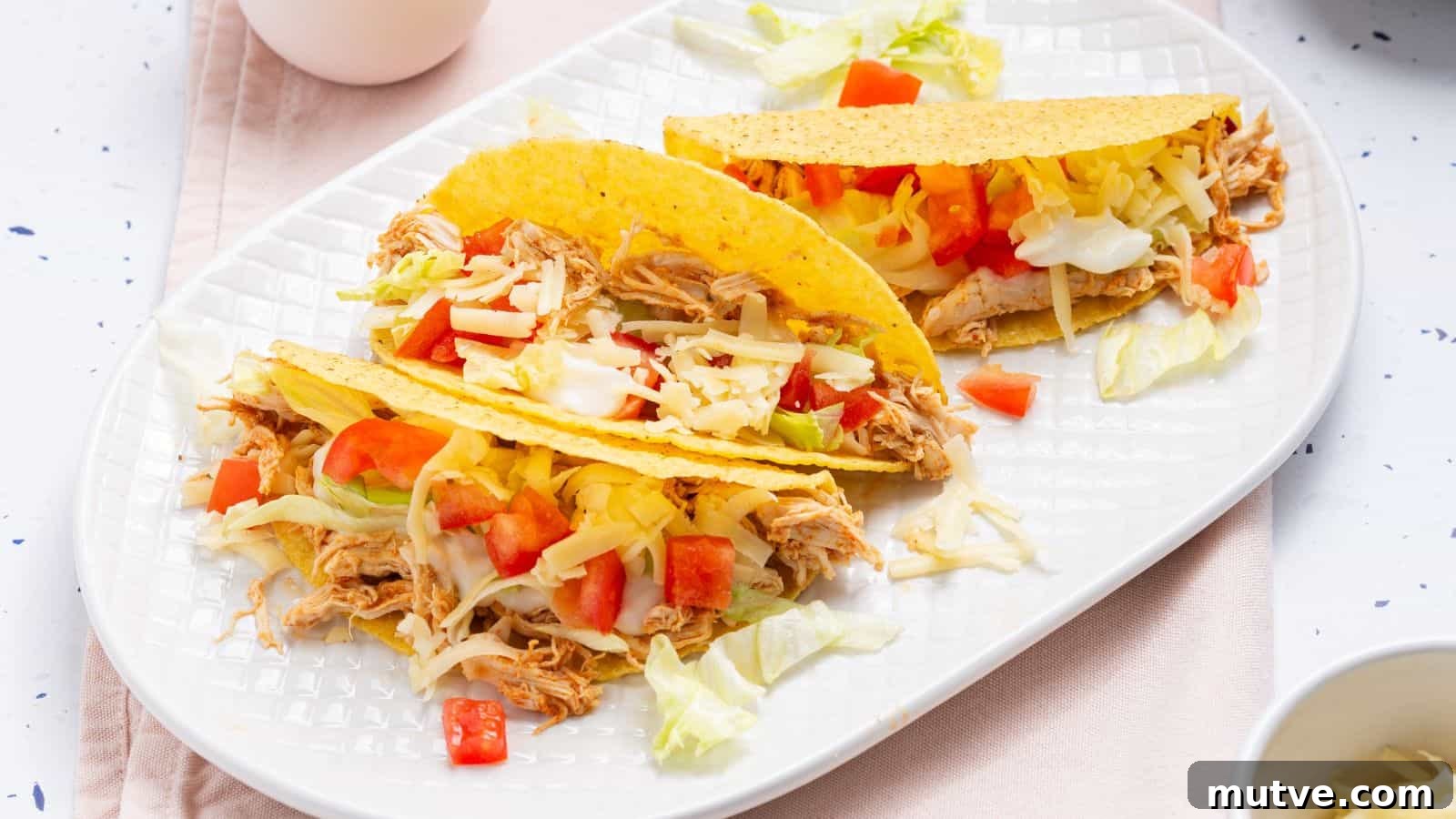 40 End-of-Summer Cookout Recipes to Celebrate Summer's Finale 10 Three chicken tacos with cheese, lettuce, and diced tomatoes on a white plate.
