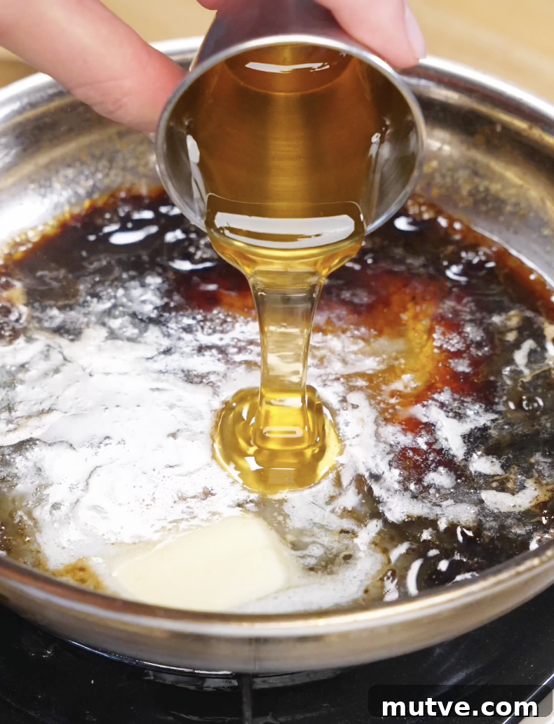 Honey being poured into a pan with butter and soy sauce, creating a glossy sauce for the Honey Butter Fried Chicken Recipe.