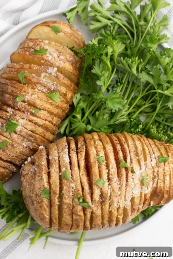 Close up sliced potatoes on a white plate with parsley garnish