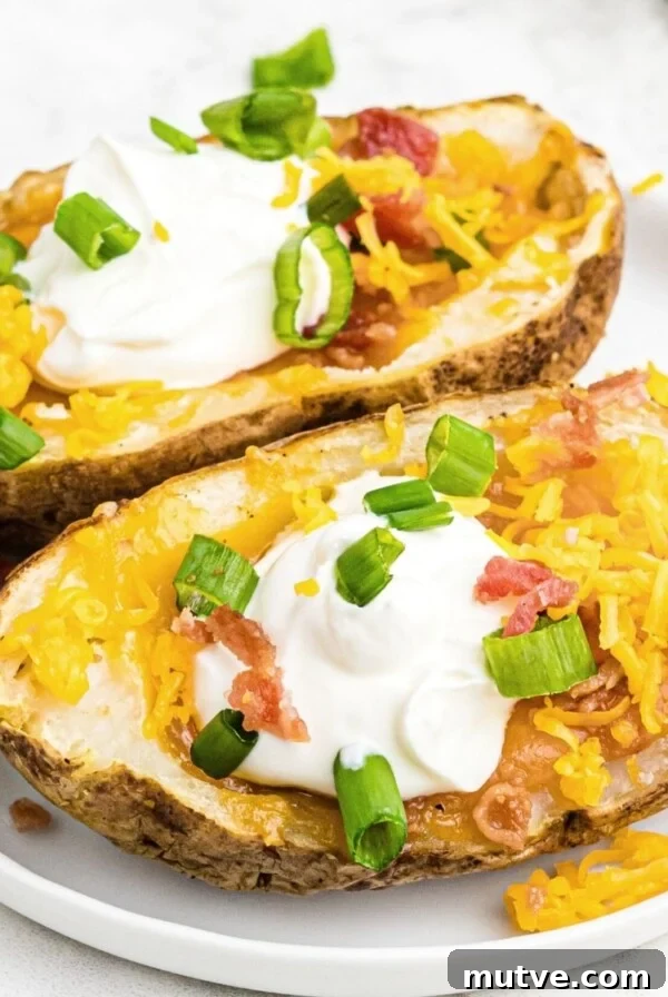 Potato skins topped with sour cream, cheese, bacon, and green onion, served on a white plate
