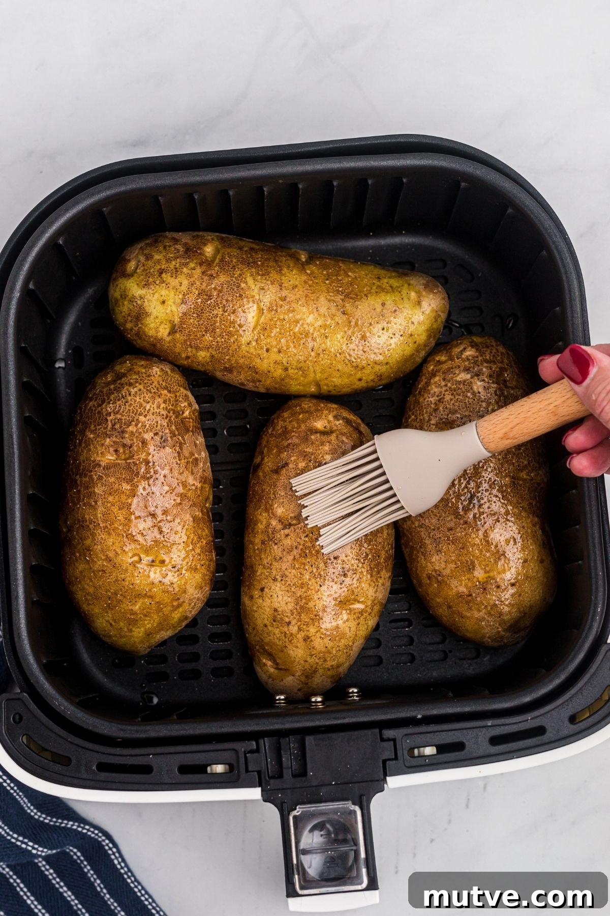 Potatoes being brushed with oil before being air fried.