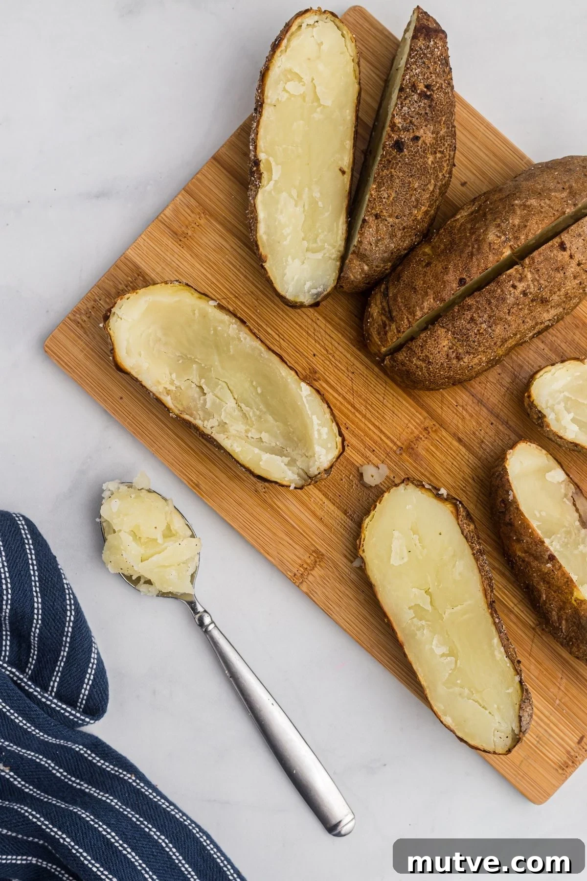 Potatoes cut in half and one scooped out with a spoon. 