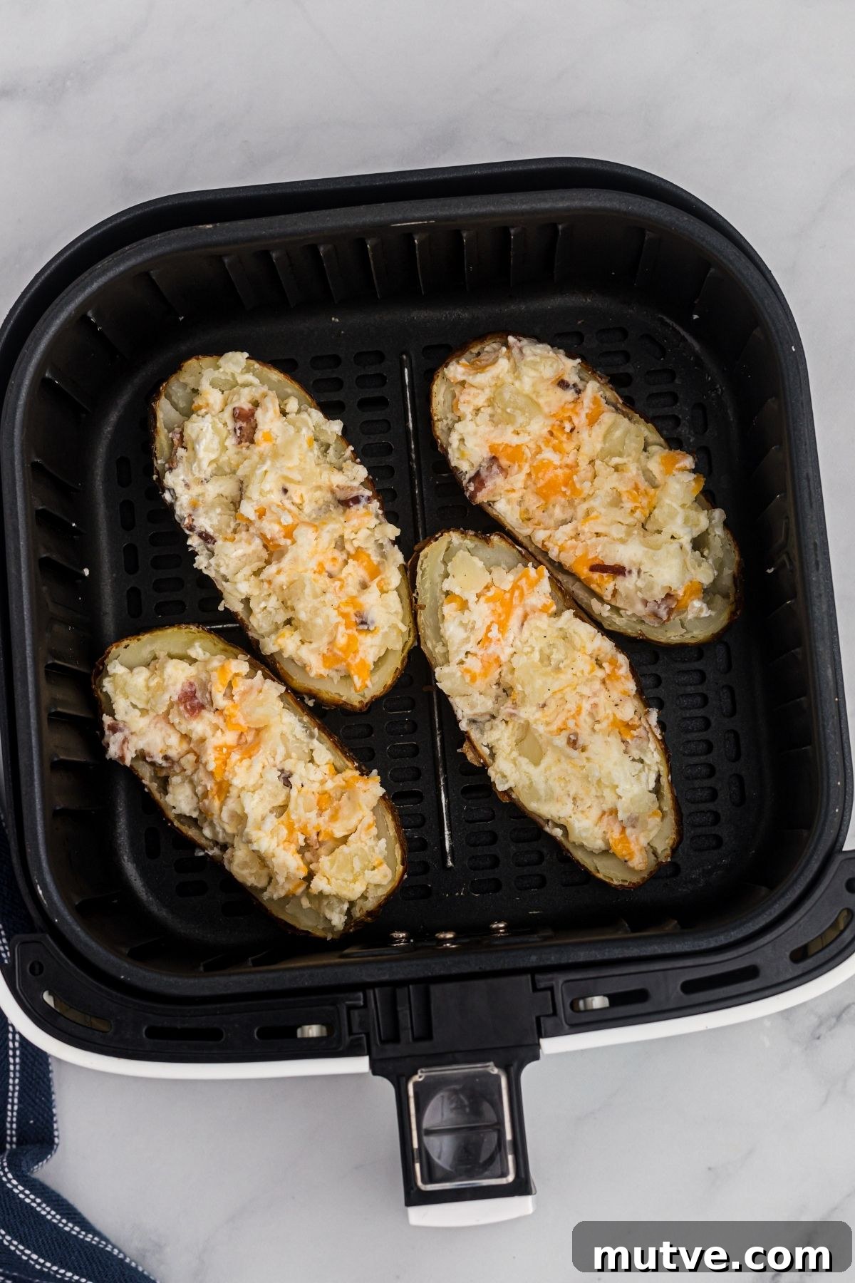 Twice baked potatoes placed in an air fryer basket. 