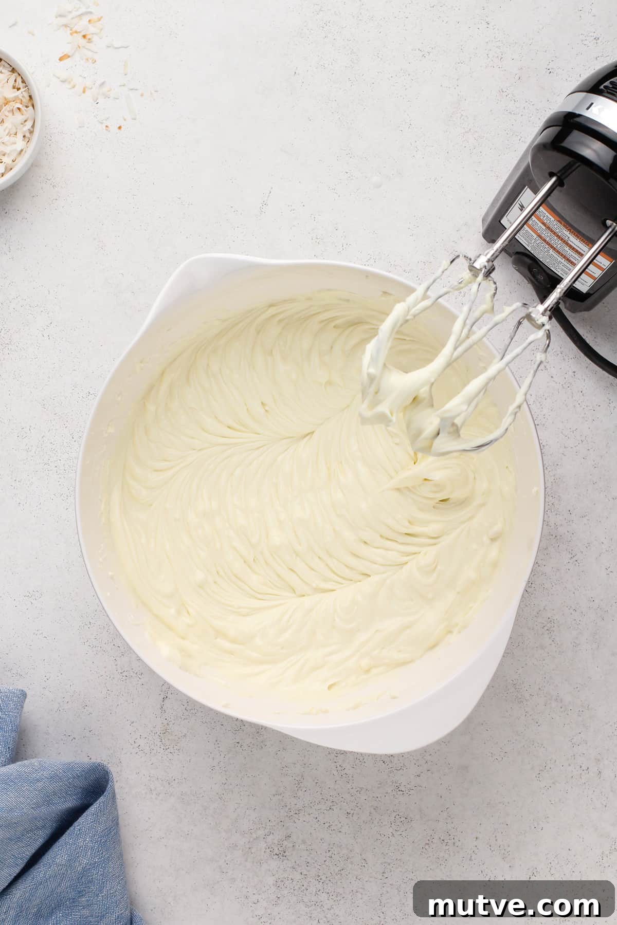 Creamy Coconut Cheesecake Recipe 10 Coconut cheesecake filling in a white mixing bowl.