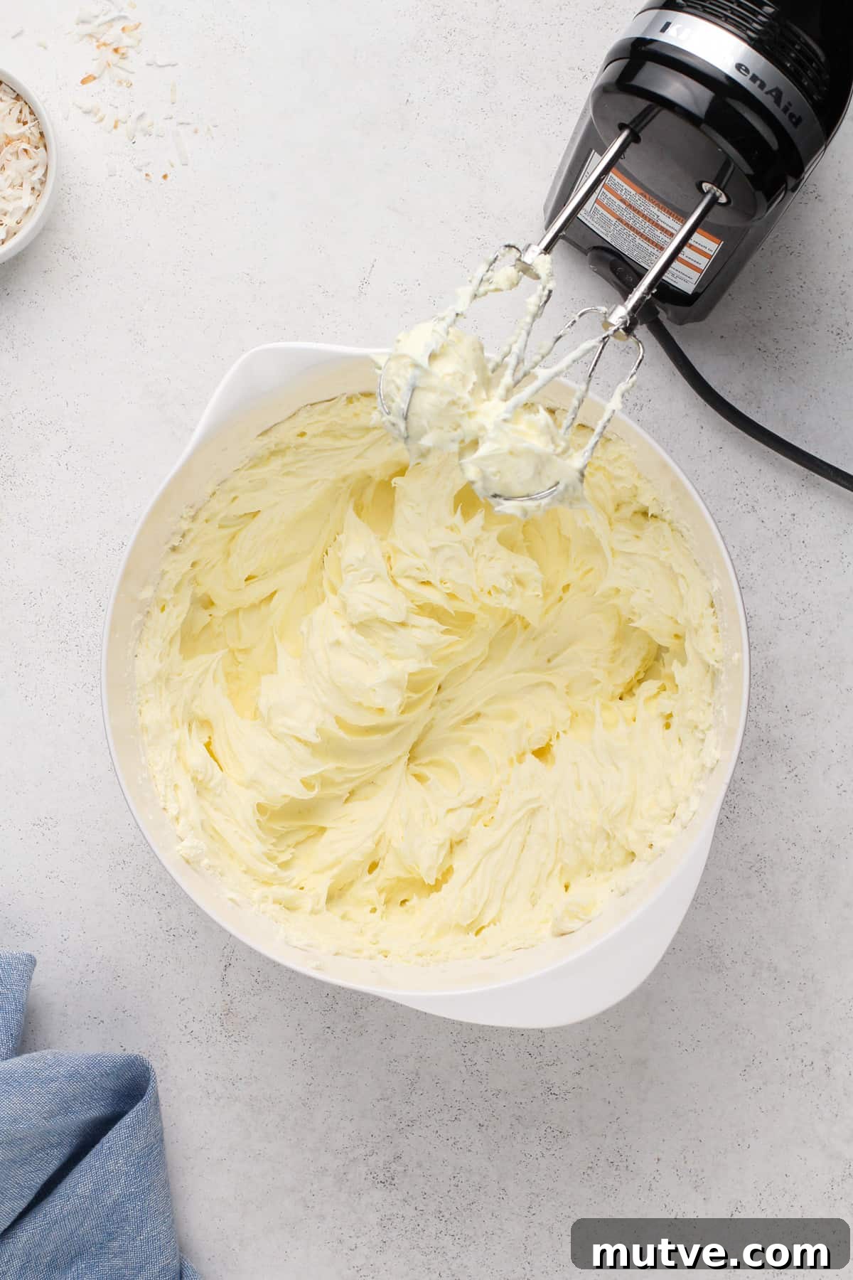 Creamy Coconut Cheesecake Recipe 8 Cream cheese whipped with sugar in a white mixing bowl.