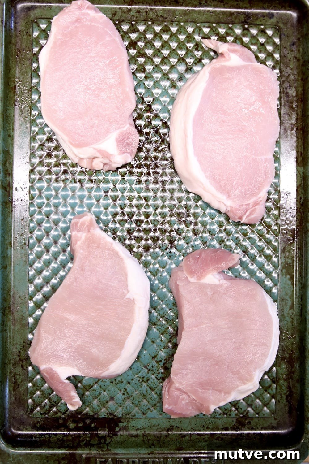 4 boneless pork chops on a blue baking sheet