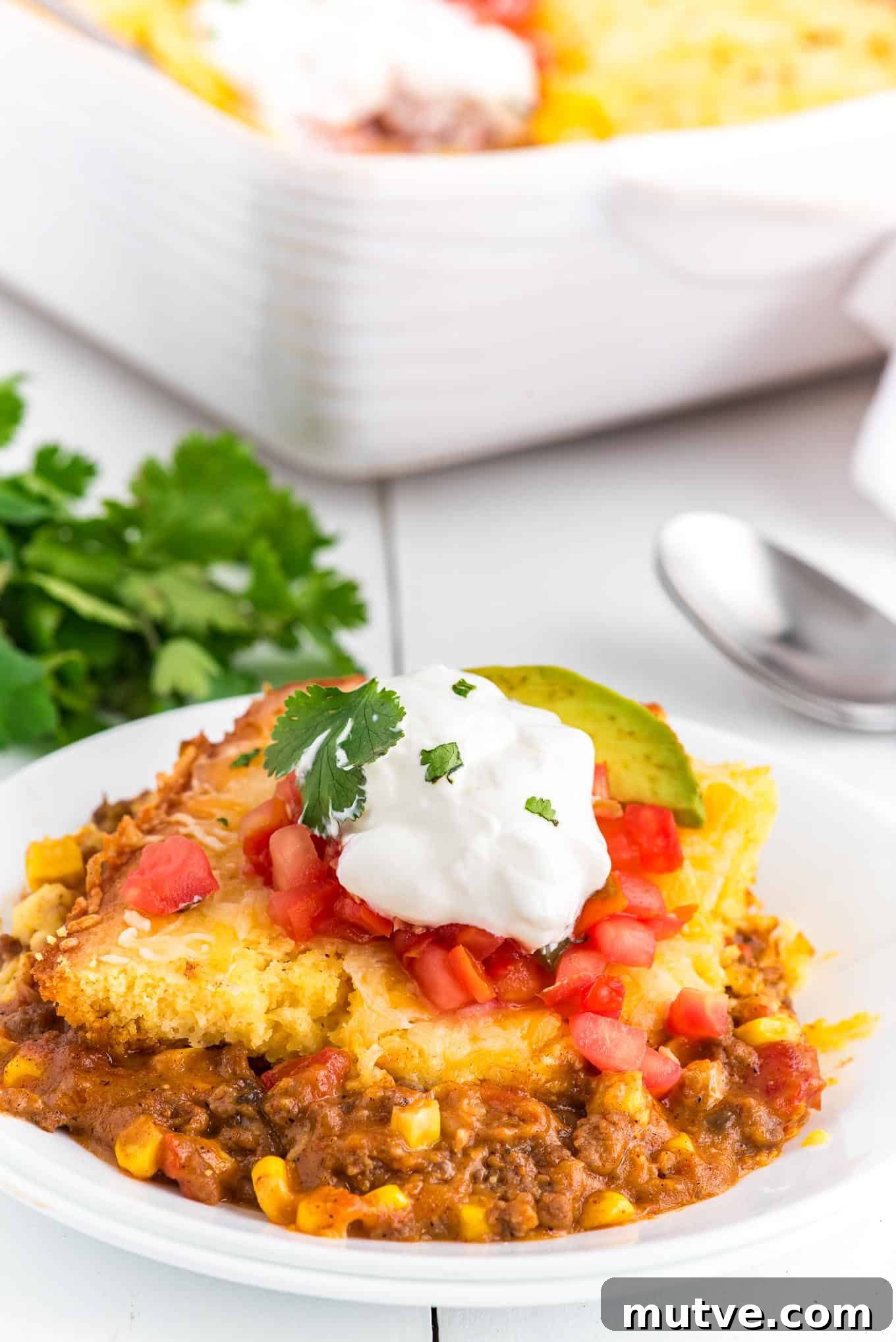 Plated Mexican corn casserole topped with sour cream.