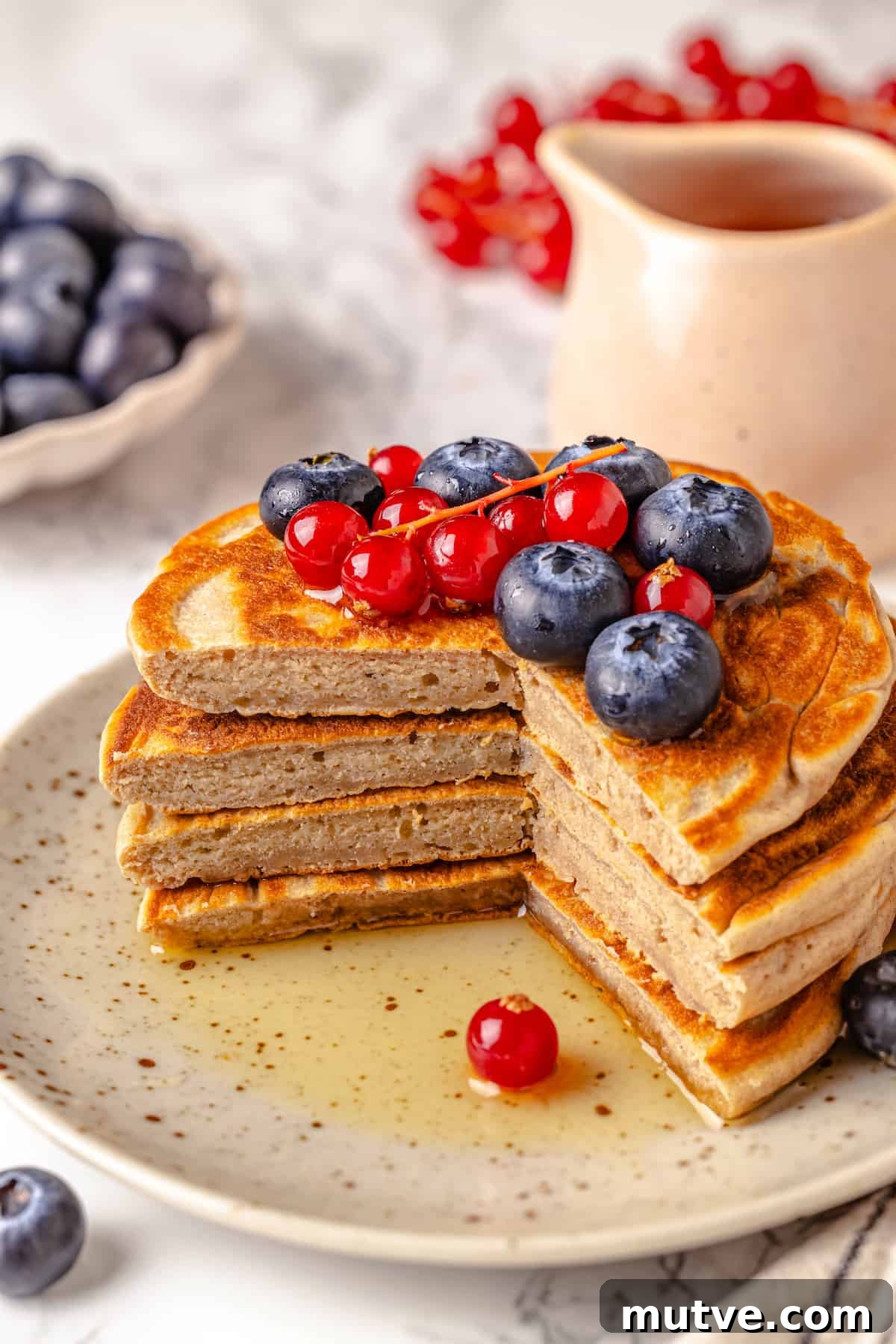 Stack of protein pancakes on plate, cut to show fluffy texture