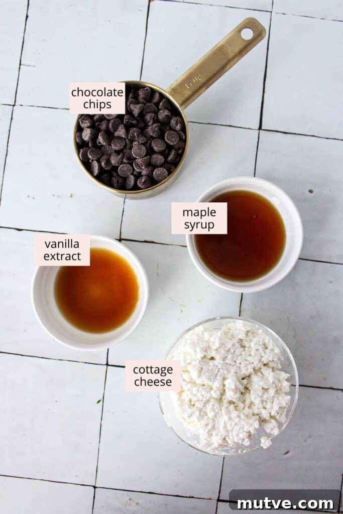 High-Protein Cottage Cheese Fudge - 4-Ingredient Recipe 3 Ingredients for cottage cheese: cottage cheese, chocolate chips, maple syrup and vanilla arranged on a countertop.