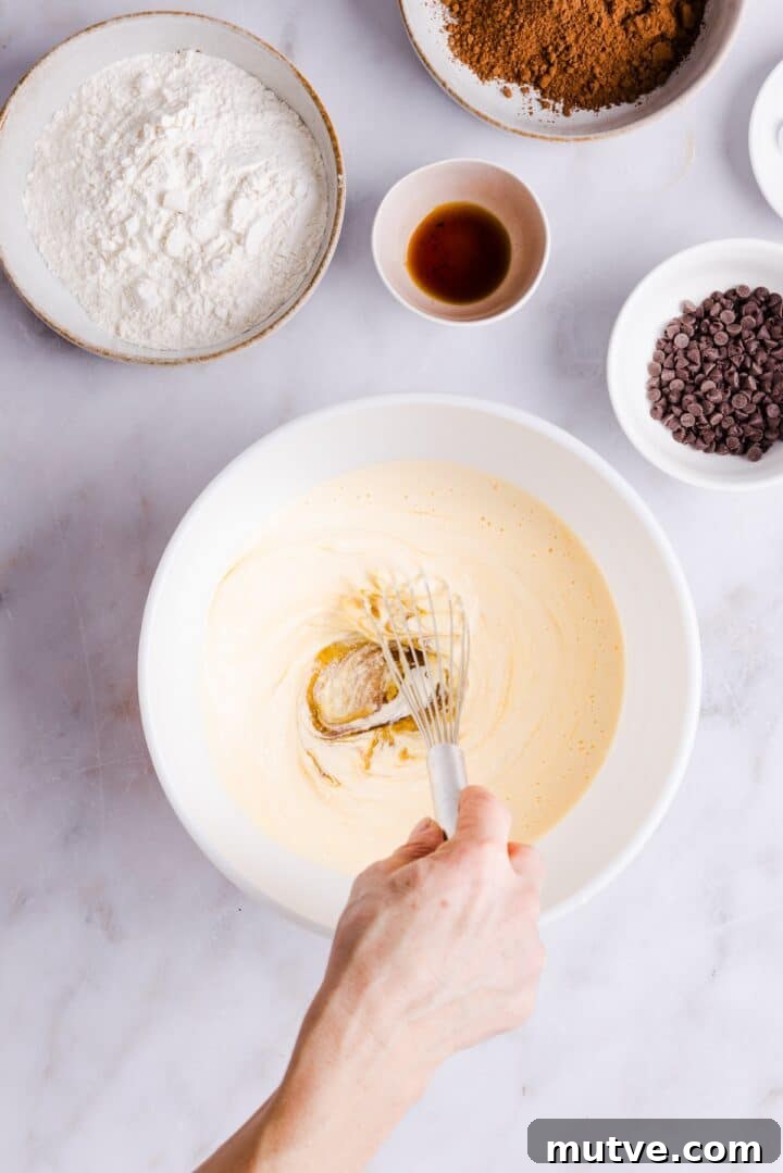 Cottage Cheese Brownies Recipe: Moist, Protein-Packed Treat 6 Woman's hand whisking blended cottage cheese mixture in a large white bowl