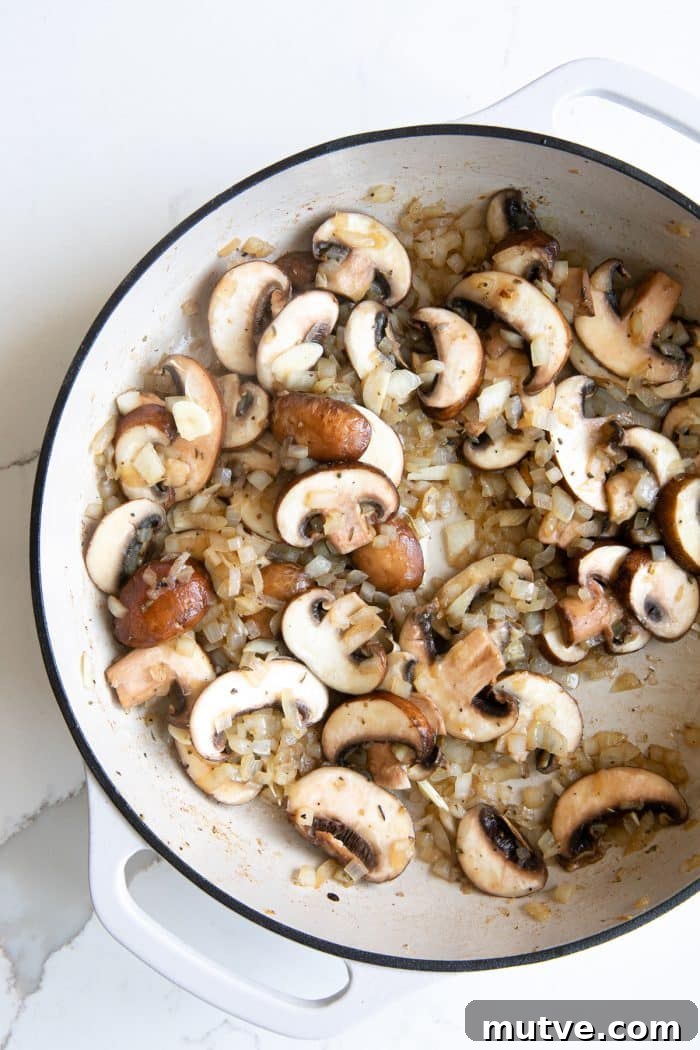 Sliced onions and mushrooms cooking in a skillet until golden and soft.