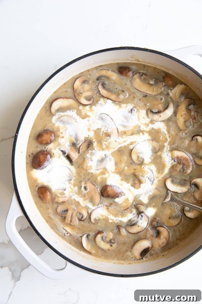 White ceramic Dutch oven filled with homemade mushroom cream sauce.