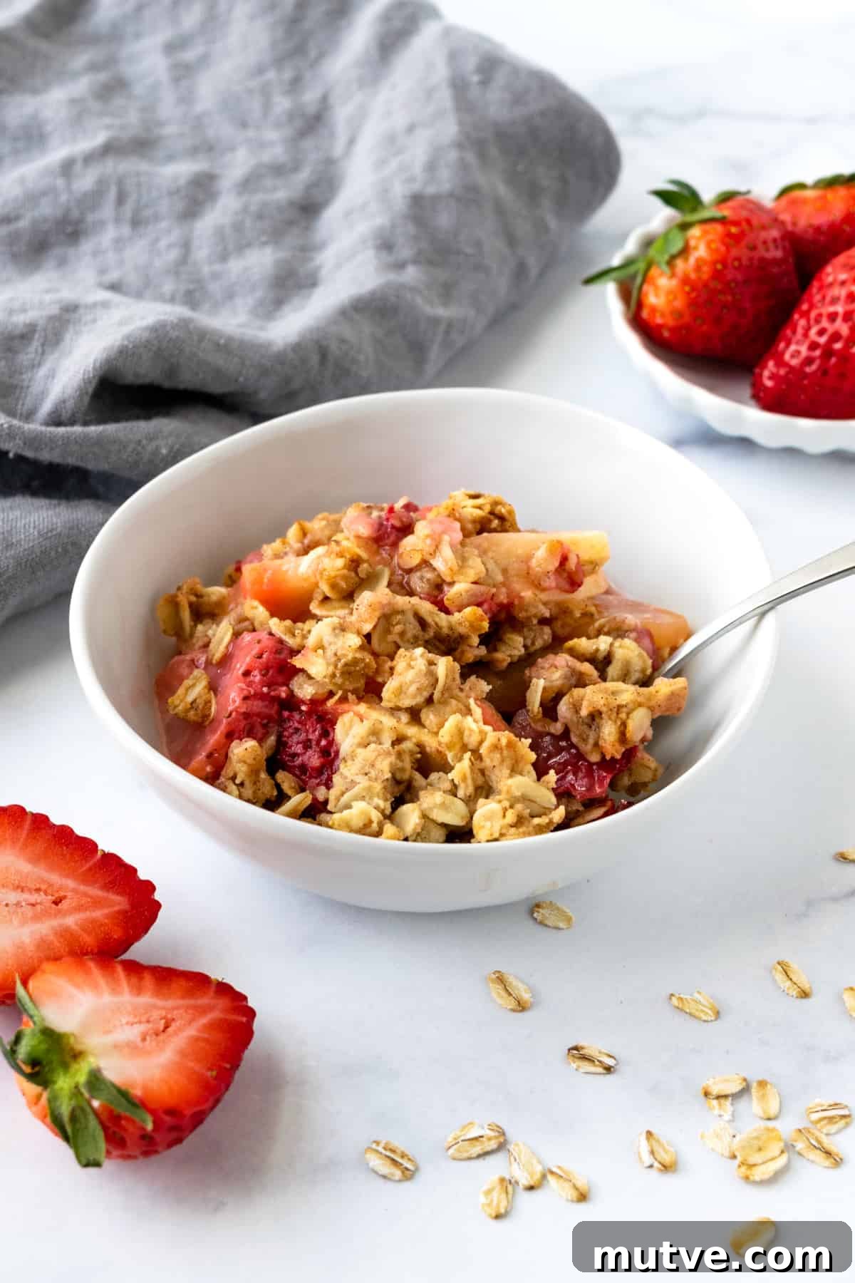 Warm Strawberry Apple Crisp Recipe with Cinnamon Oat Topping 2 Strawberry Apple Crisp in a white bowl with a spoon.