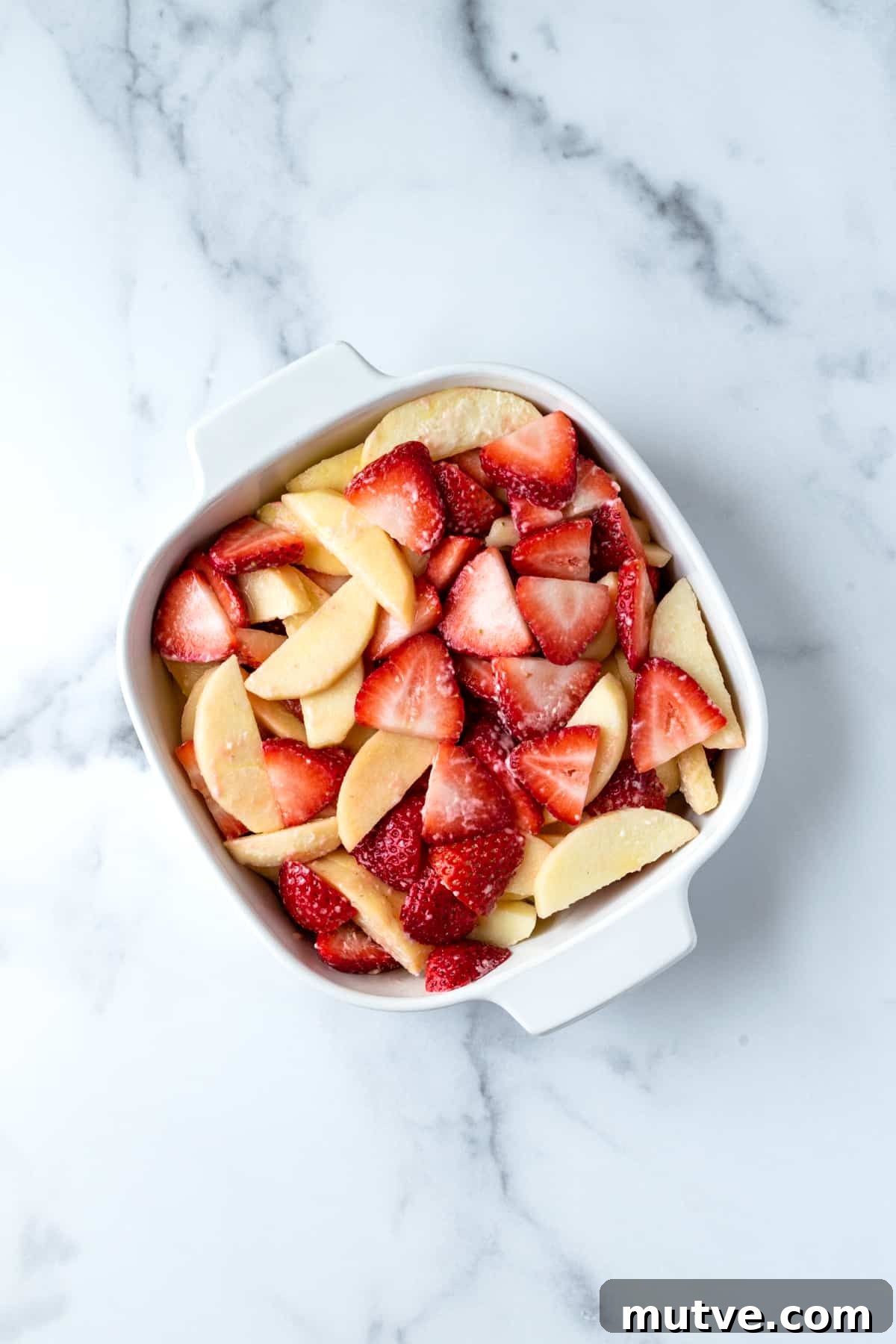 Warm Strawberry Apple Crisp Recipe with Cinnamon Oat Topping 6 Strawberry and Apple Slices in a white baking dish.