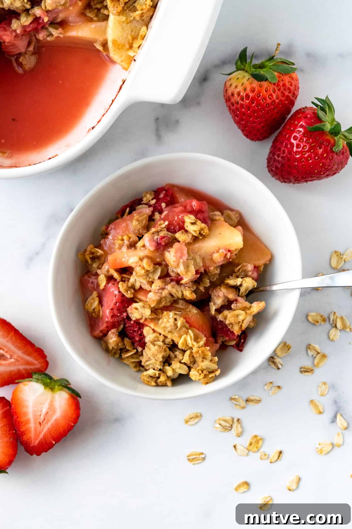 Warm Strawberry Apple Crisp Recipe with Cinnamon Oat Topping 8 Strawberry Apple Crisp in a white bowl with a spoon.