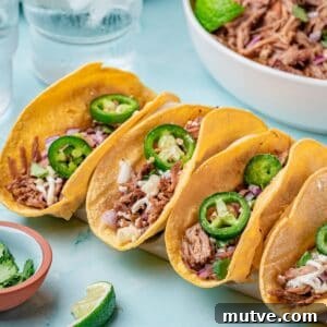 Slow Cooker Pulled Pork Tacos on blue background in taco holders