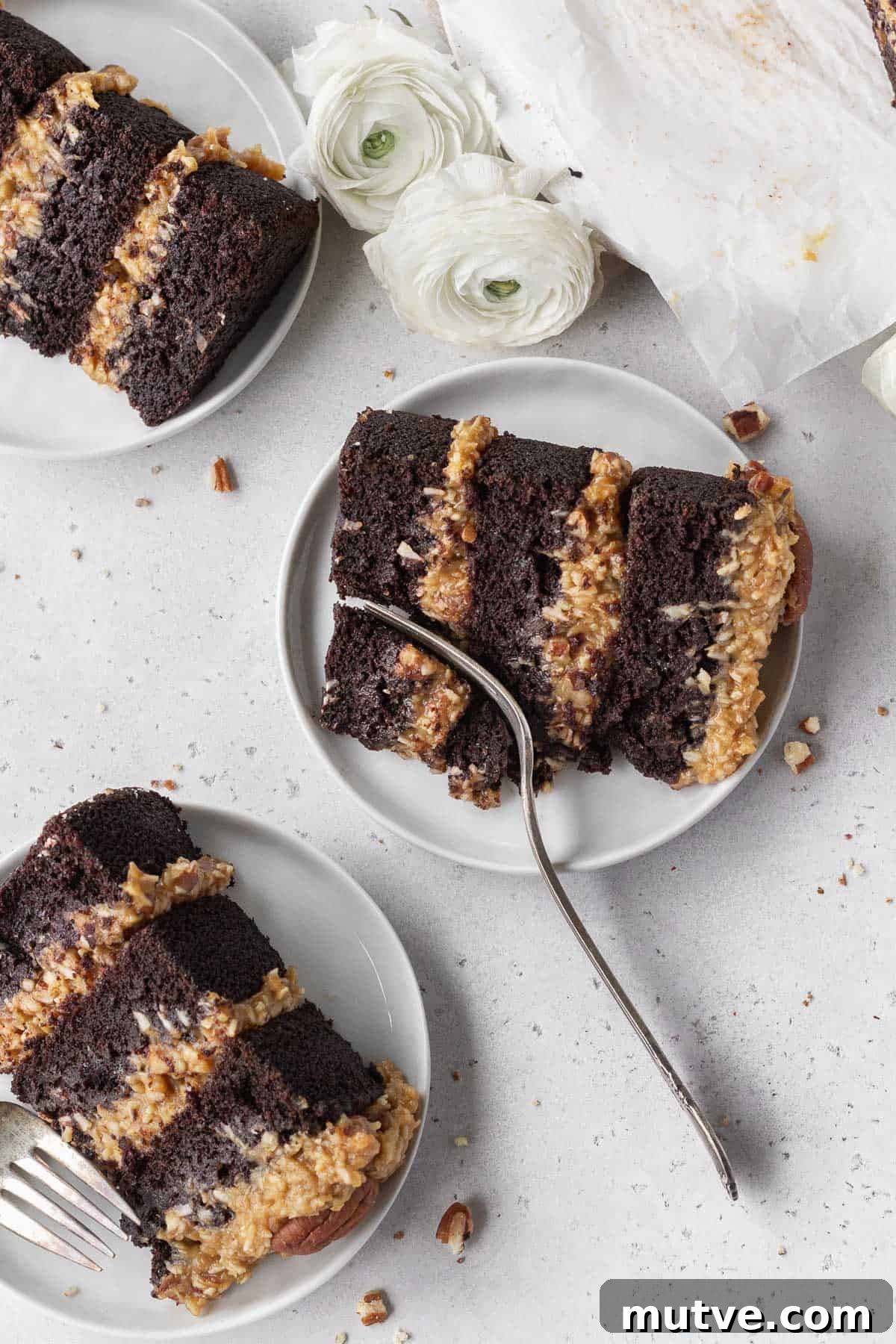 An overhead shot of three small white plates with a slice of gluten free German chocolate cake placed on each one.