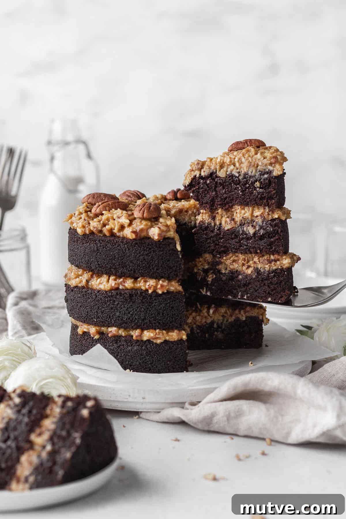 A gluten-free German chocolate cake with a slice being taken out.