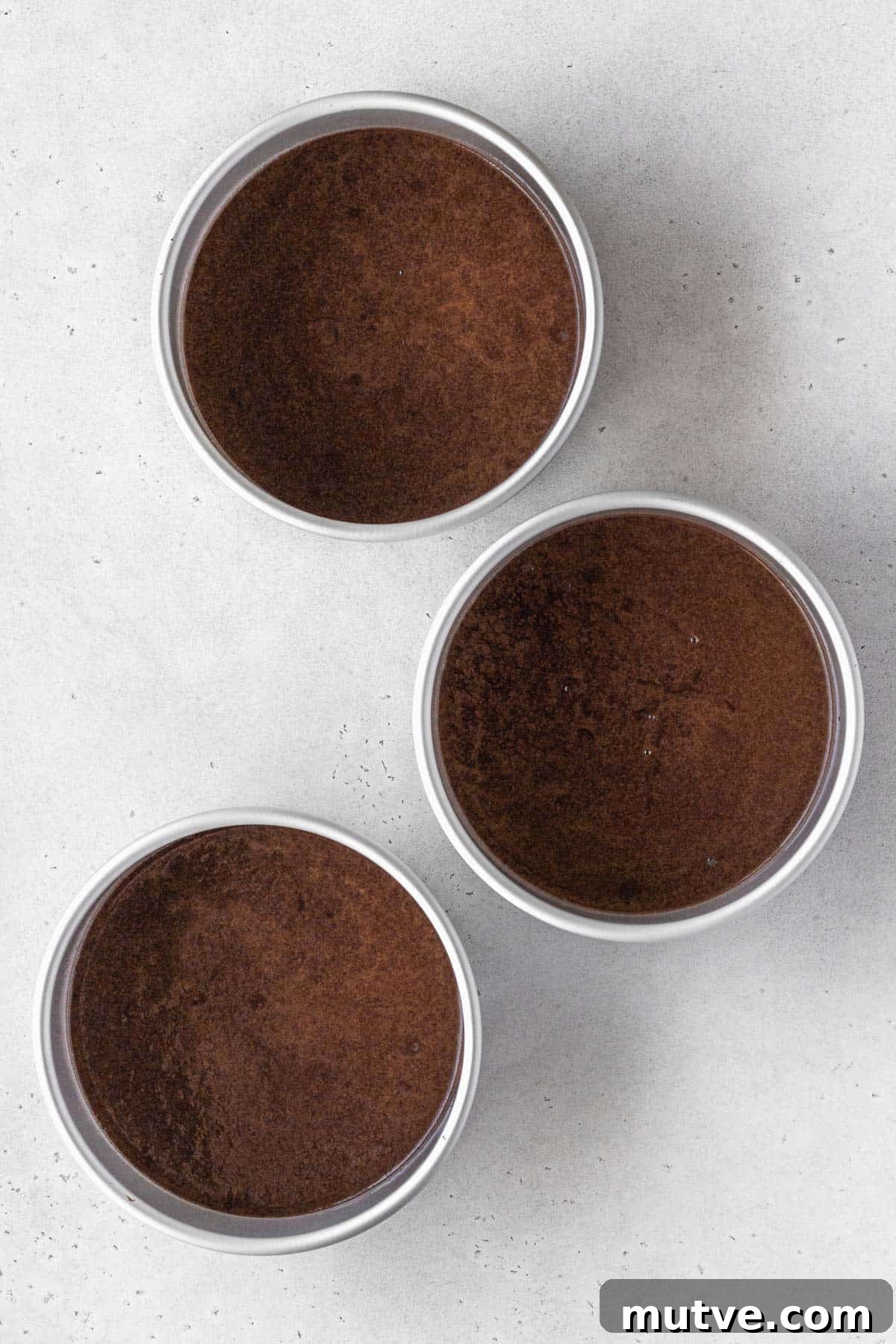 German chocolate cake batter in three 6 inch round cake pans.
