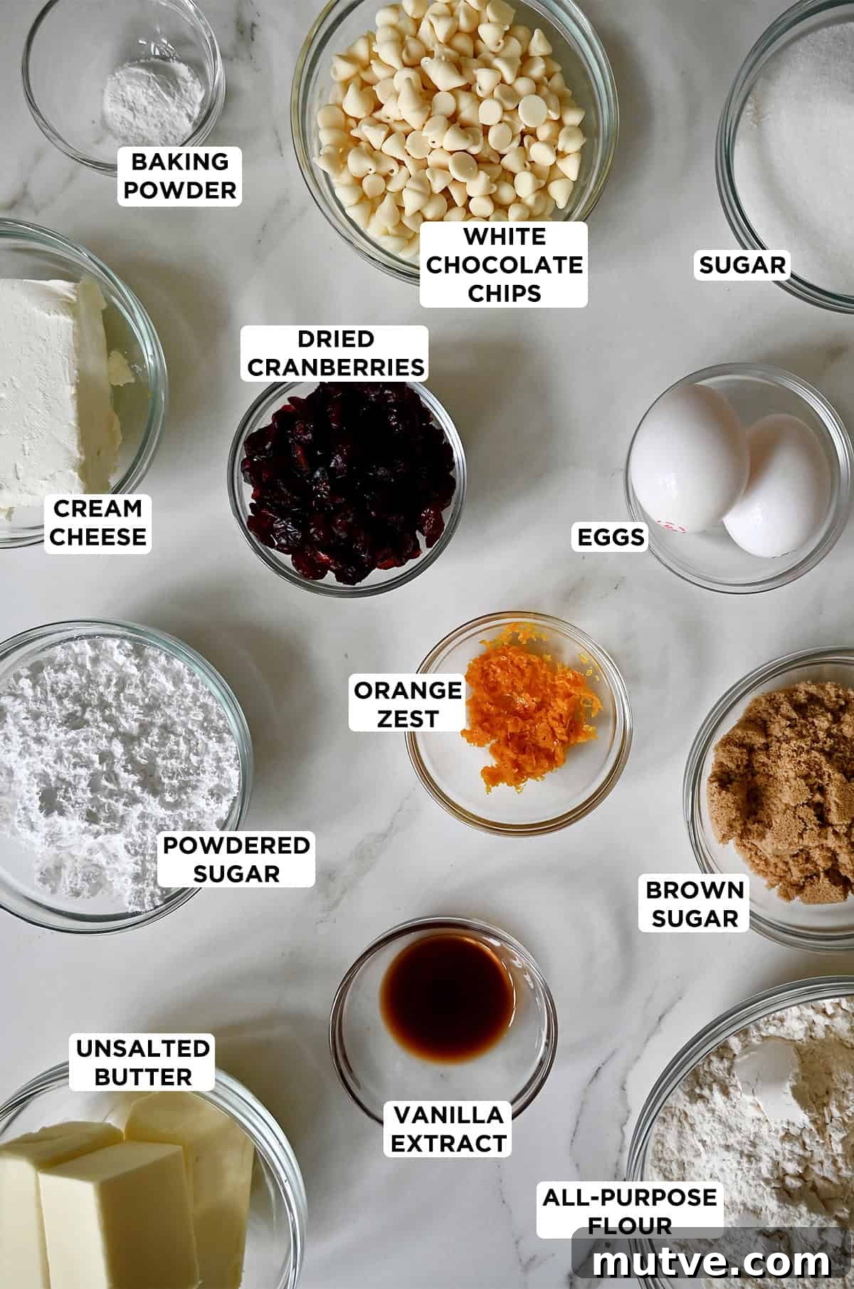 All of the ingredients needed to make cranberry bliss bars in various sizes of glass bowls.