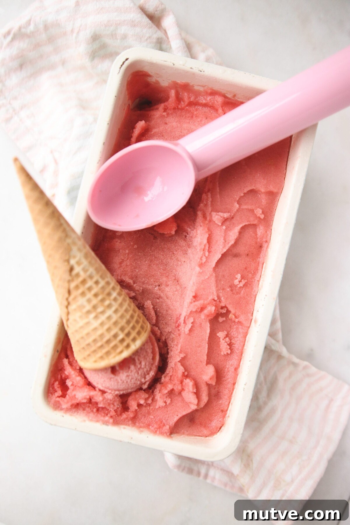 a white dish filled with sugar free sorbet with a pink scooper resting on top