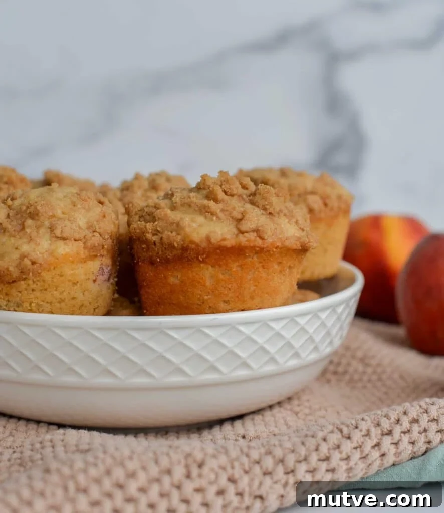 Moist Sourdough Peach Muffins Recipe 3 Sourdough peach muffins with a crumb topping sitting in a bowl