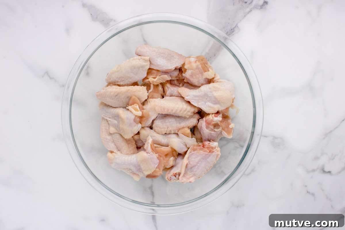 Extra Crispy Oven-Baked Chicken Wings Recipe 4 chicken wings in a clear glass bowl on counter.